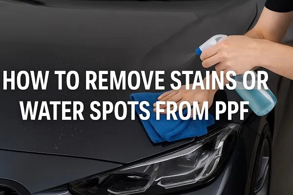 Person cleaning water spots from a car’s PPF with a spray bottle and microfiber towel.